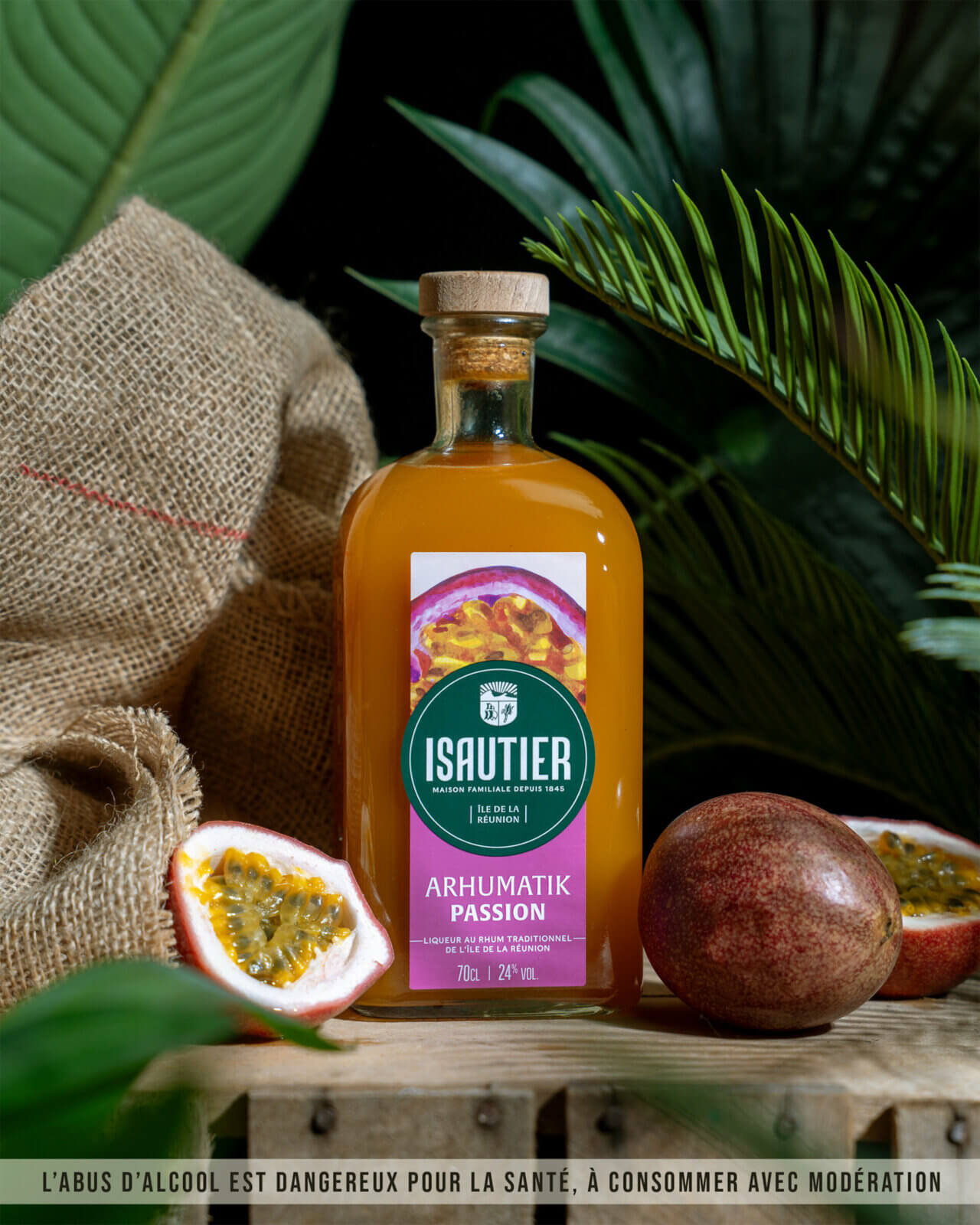 Bouteille d’Arhumatik Isautier Passion posée dans un décor végétal avec fruits de la passion.
