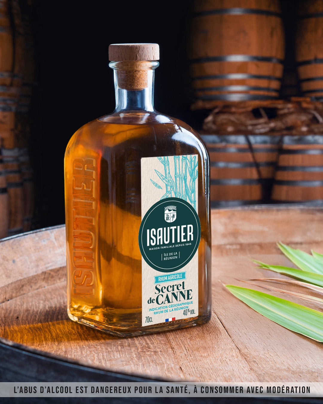 Bouteille de rhum brun Isautier Secret de canne posée sur un tonneau.