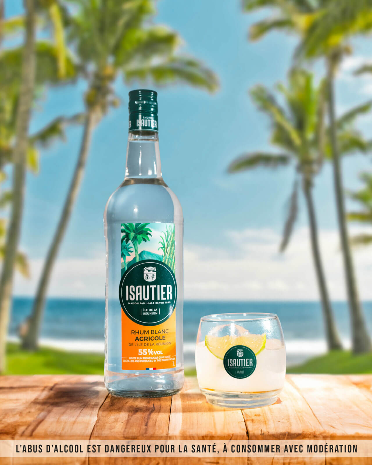 Bouteille de rhum blanc agricole Isautier 55 % posée sur une table en bois avec un verre, en bord de mer.