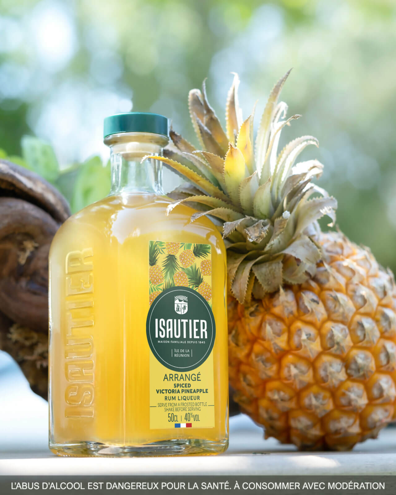 Isautier Arrangé Spiced Victoria Pineapple rum liqueur bottle displayed with fresh pineapple
