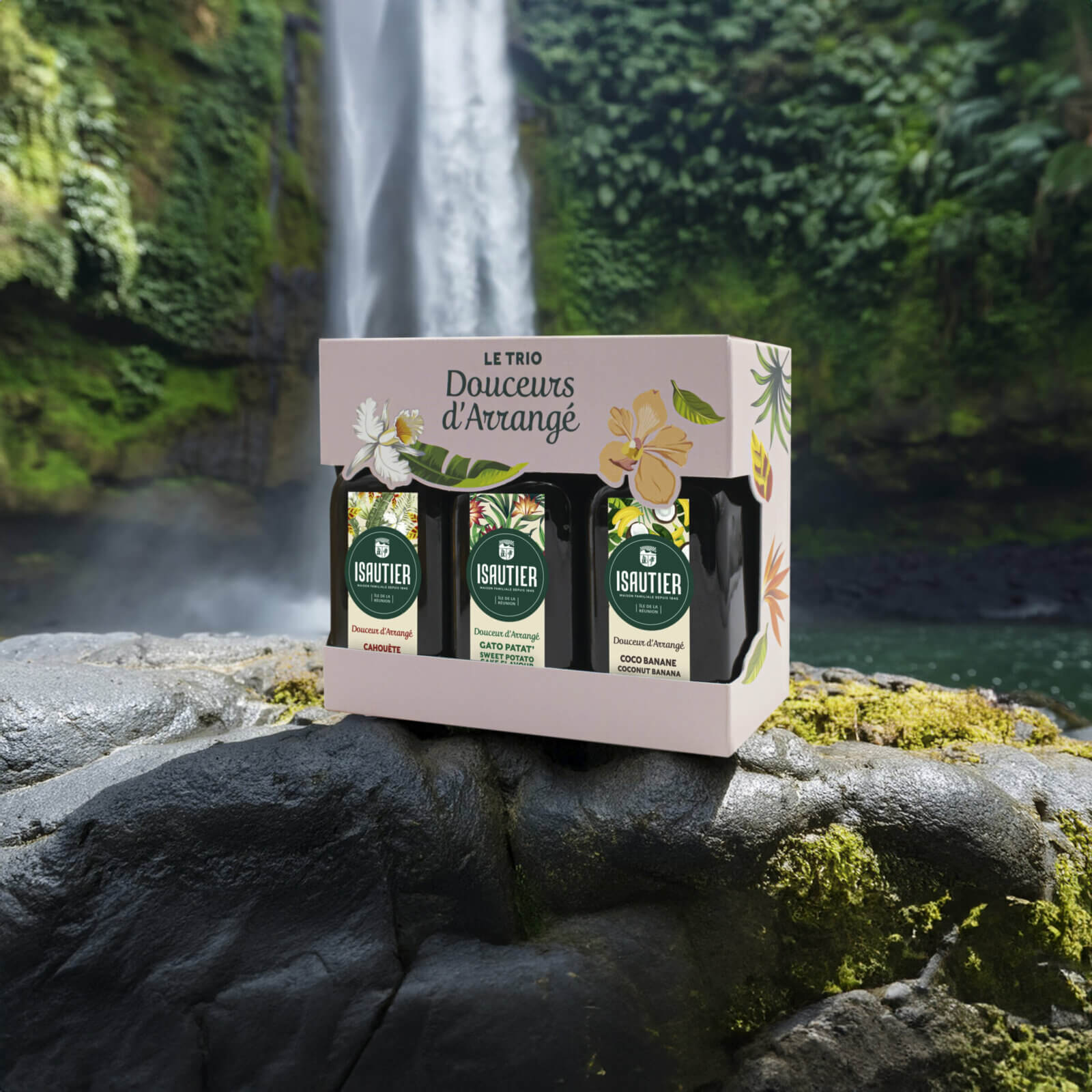 Coffret Trio Douceurs d’Arrangé Isautier posé sur un rocher devant une cascade tropicale.