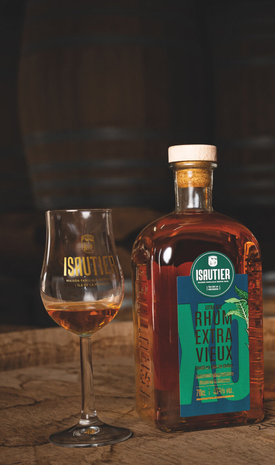 Bouteille de Rhum Extra Vieux Isautier posée sur une table en bois avec un verre, dans un décor évoquant un chai.