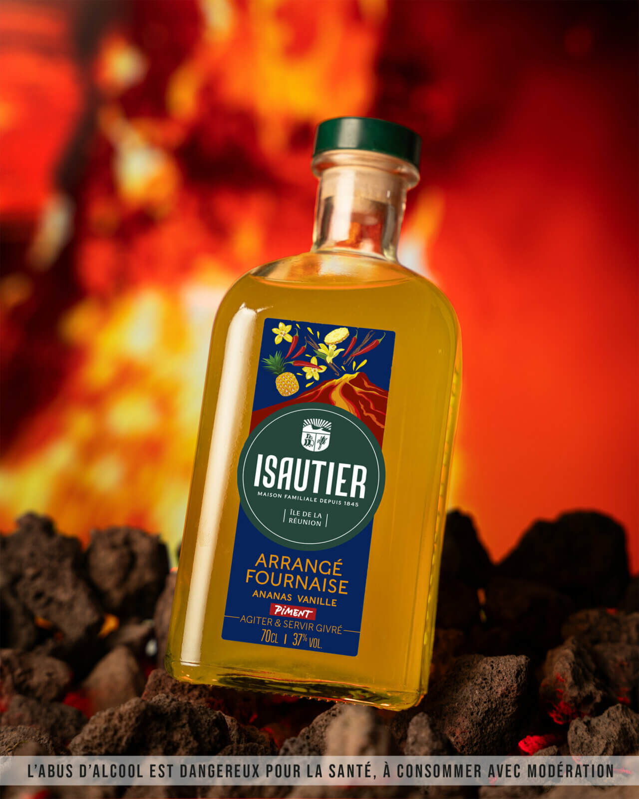 Bouteille de rhum arrangé Isautier « Arrangé Fournaise Ananas Vanille Piment » posée sur des roches volcaniques devant un fond de lave enflammée