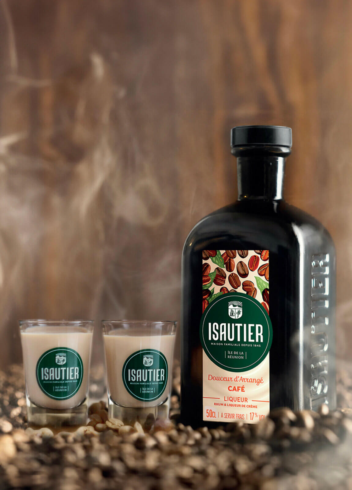 Bouteille de liqueur Douceur d’Arrangé Café Isautier avec deux verres servis, posée sur un lit de grains de café