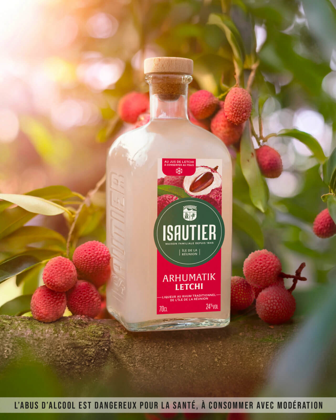 Bouteille d’Arhumatik Isautier Letchi posée parmi des letchis dans un décor naturel.