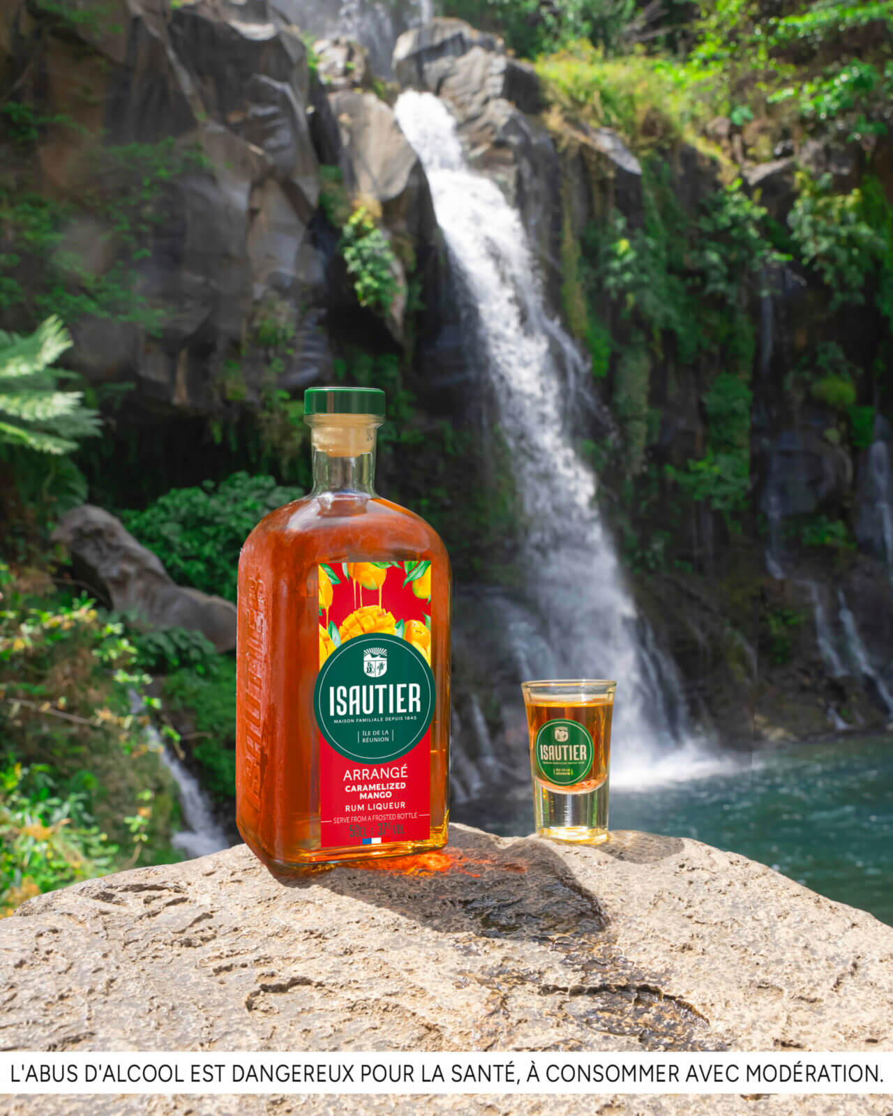 Isautier Arrangé Caramelized Banana rum liqueur bottle displayed in a tropical waterfall setting